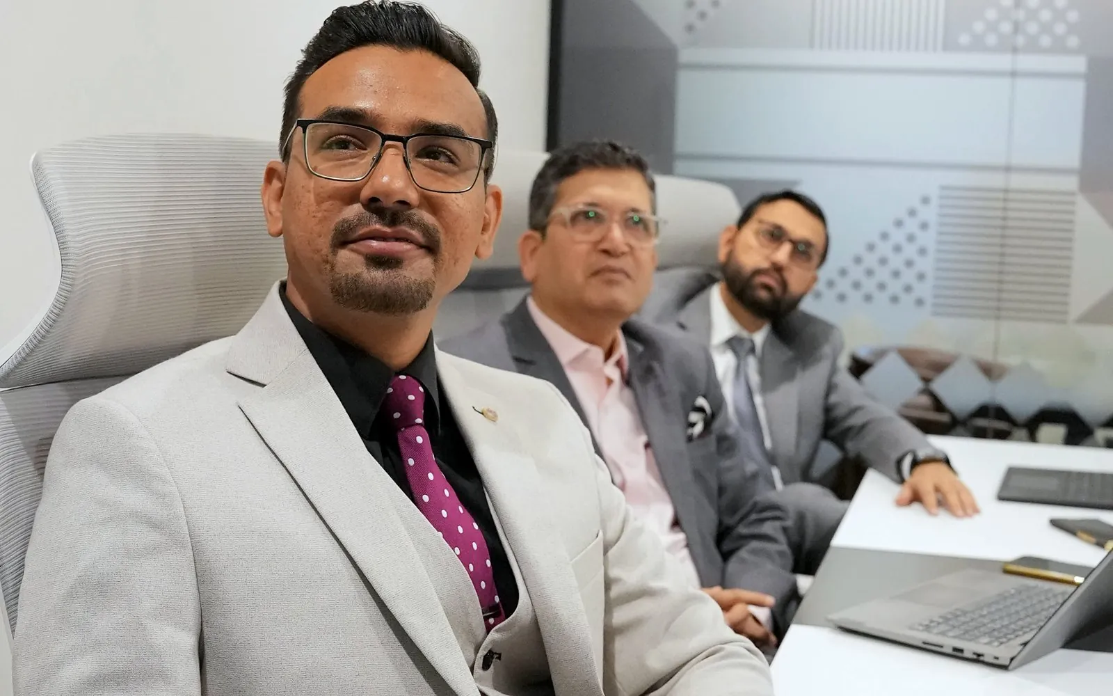 Mazahir leading a meeting in the boardroom with two colleagues.